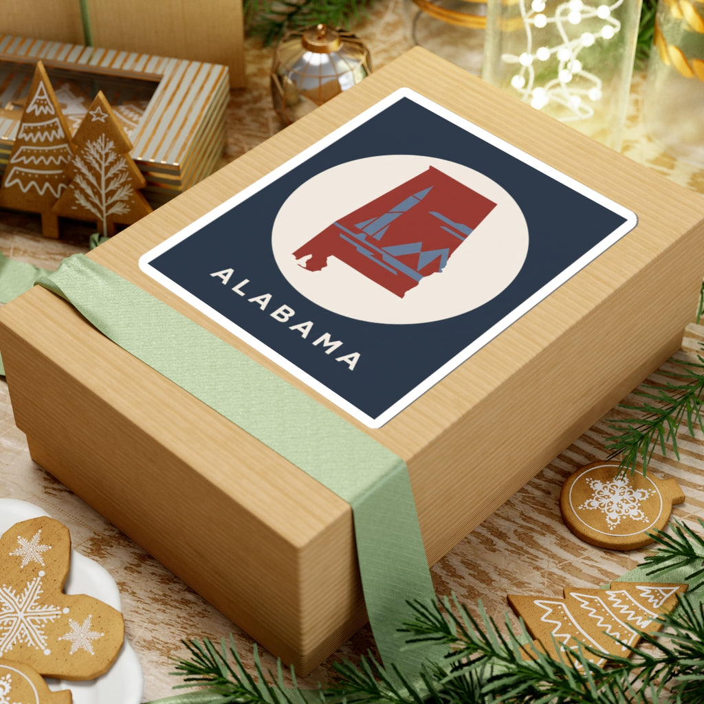 Square kiss-cut Alabama sticker on a gift: red landmark in white circle, navy background