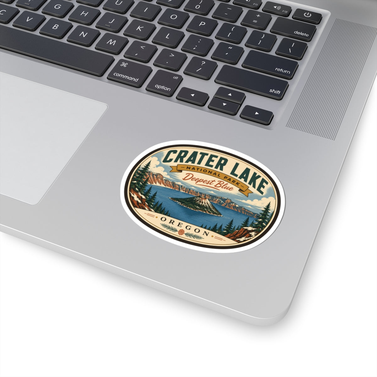 Round travel sticker on laptop trackpad, featuring Crater Lake “Deepest Blue” and “Oregon”.