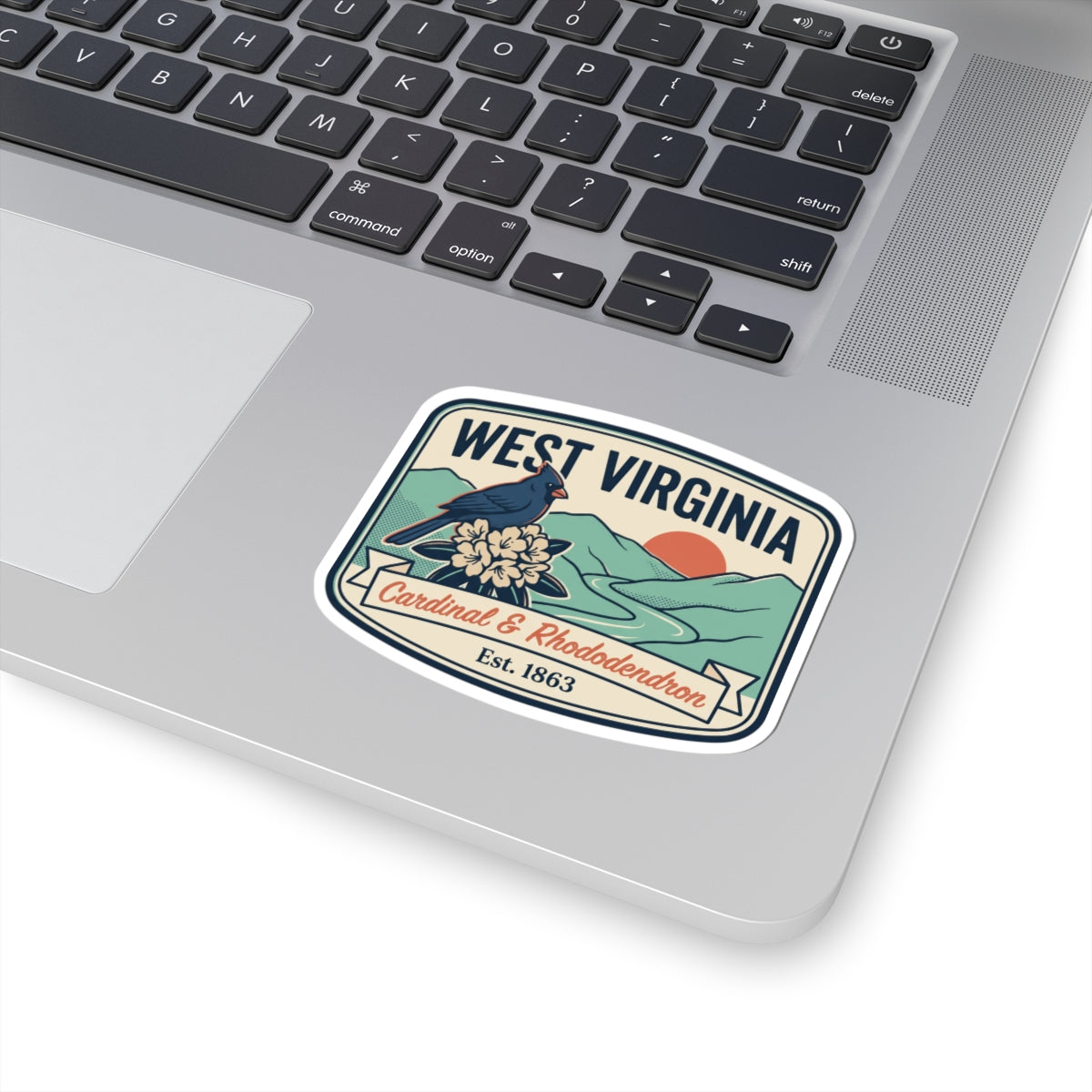 West Virginia state badge sticker on laptop, cardinal and rhododendron, Est. 1863.