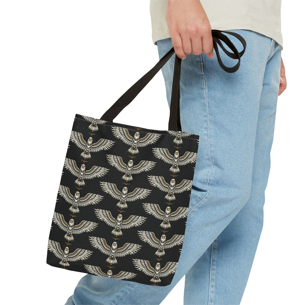 Winged scarab tote bag in black with gold emblems, held by straps, long handles