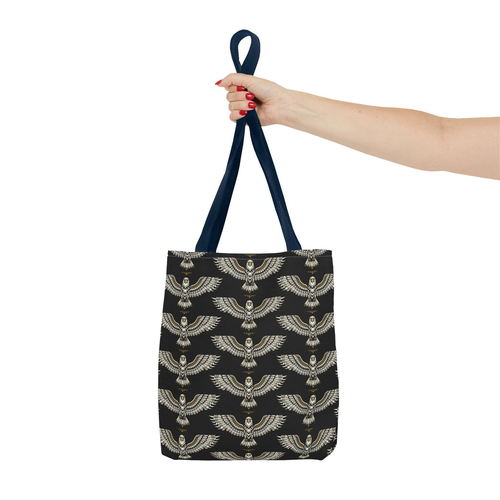 Black tote bag with winged scarab pattern and pale gold details; top handle held up
