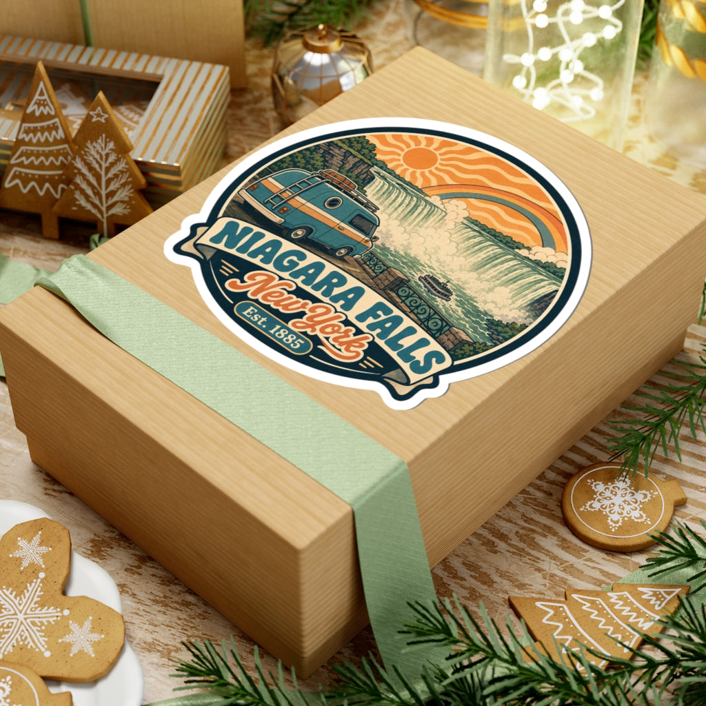 Round kiss-cut vinyl sticker on a gift box with teal camper, Niagara Falls text, and rainbow
