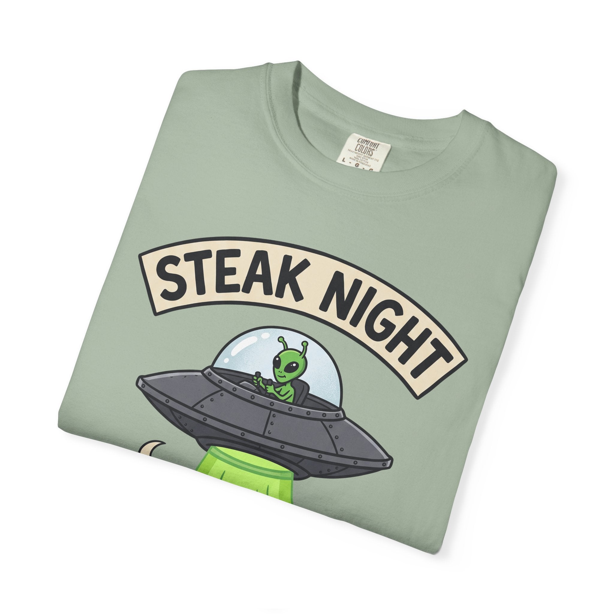 Sage green graphic T-shirt with 'STEAK NIGHT' UFO and alien cow illustration.