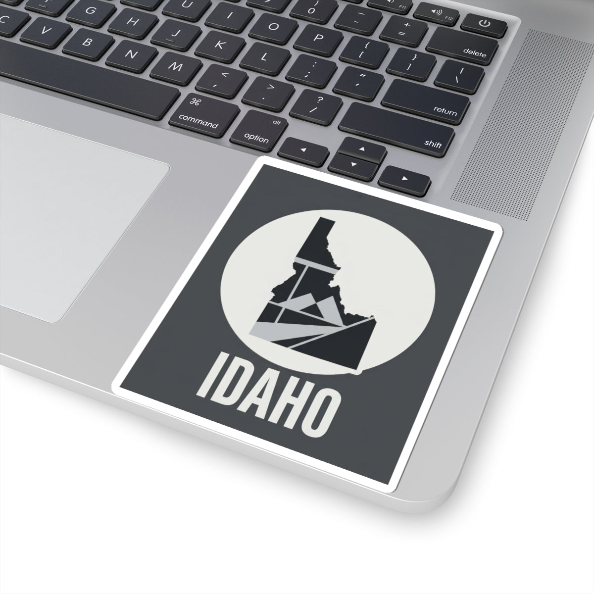 Idaho geometric map kiss-cut sticker, angled view of dark square design with white circle and IDAHO