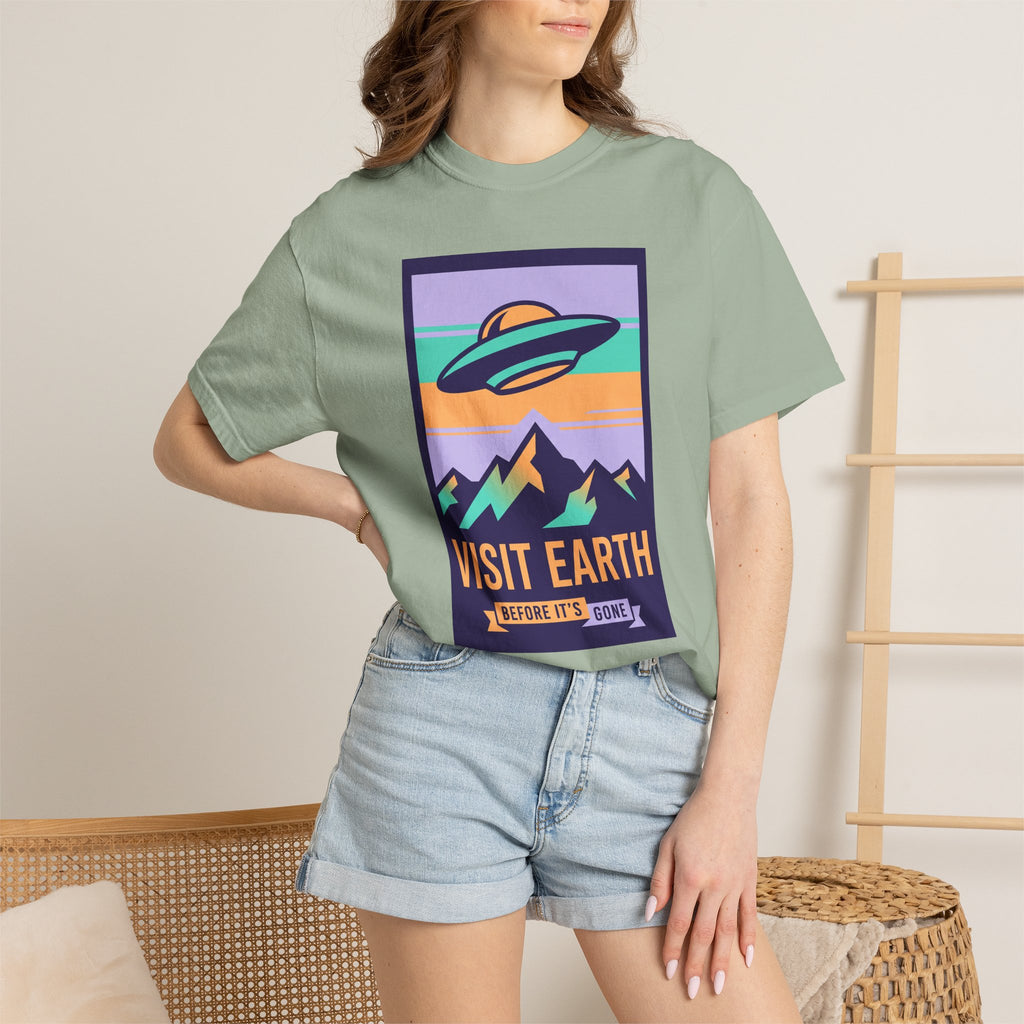 Sage green T-shirt with square UFO poster graphic and 'VISIT EARTH' lettering.