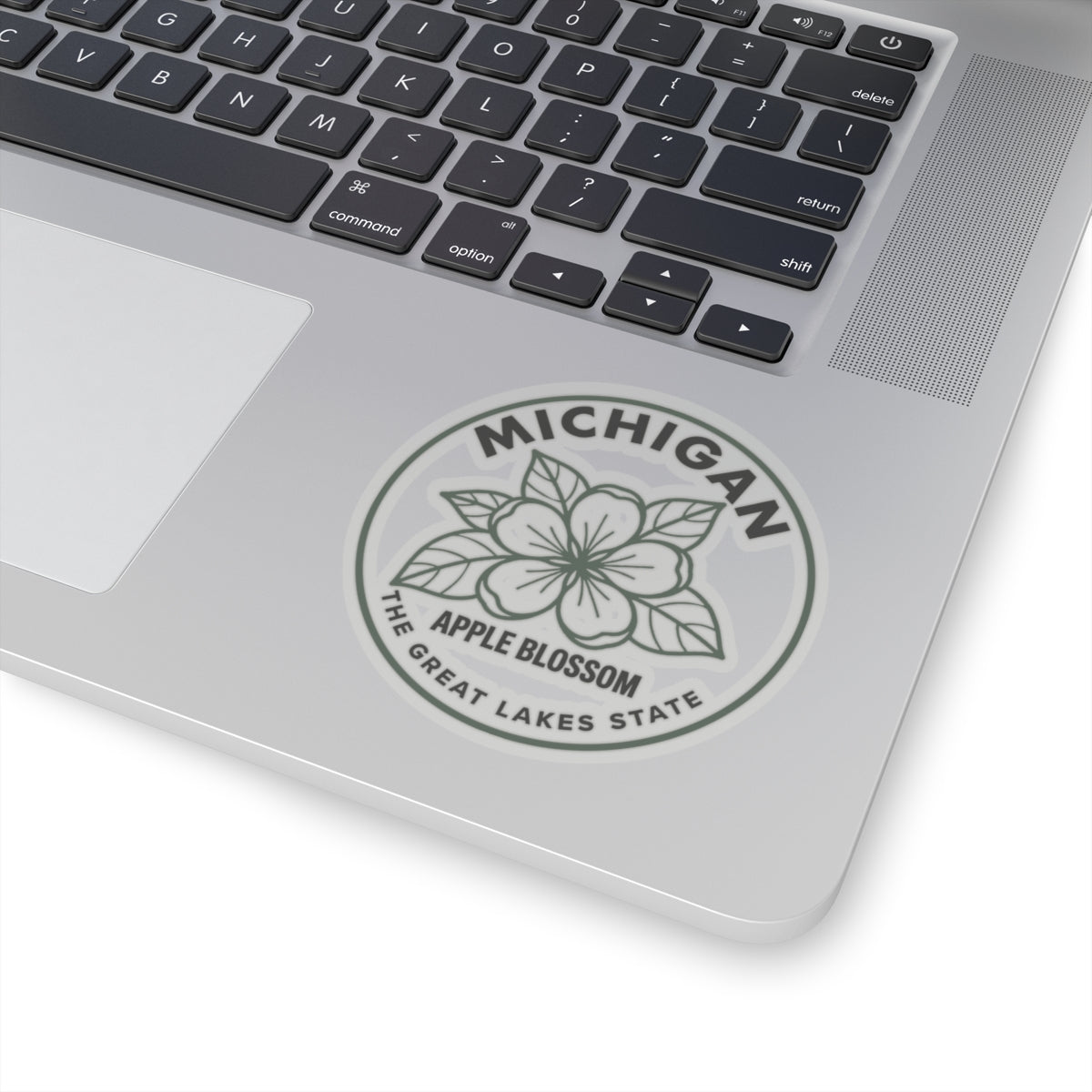 Transparent vinyl apple blossom sticker on laptop, circular Michigan logo seal with outline flower