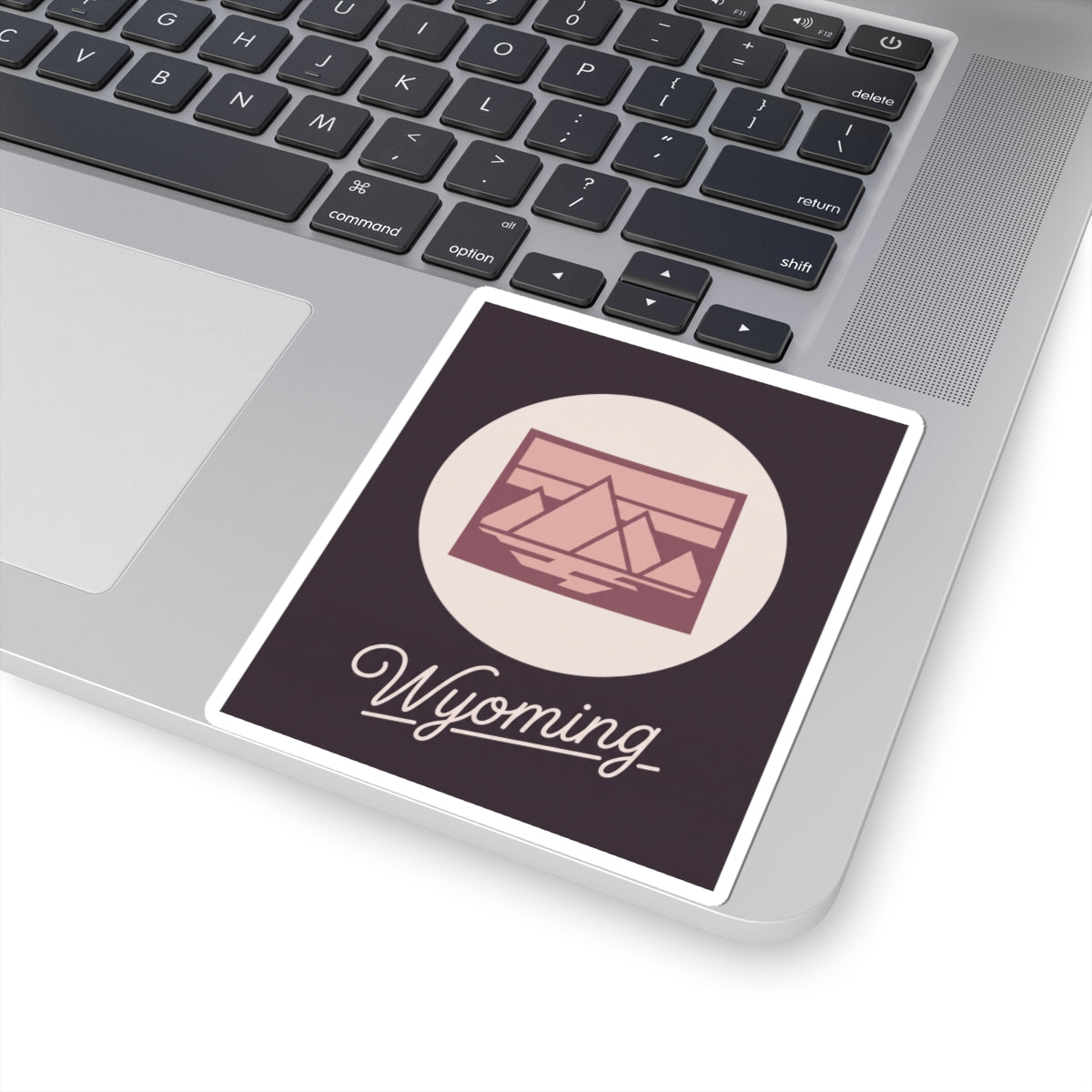 Wyoming kiss-cut decal on laptop keyboard with pink landscape graphic and “Wyoming”