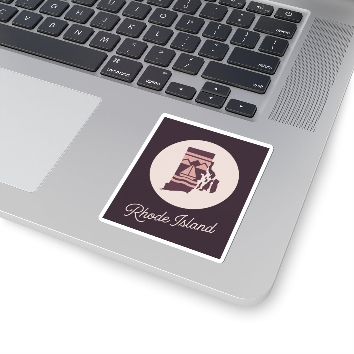 Rhode Island state silhouette decal on laptop surface, circular lighthouse emblem and 'Rhode Island' text