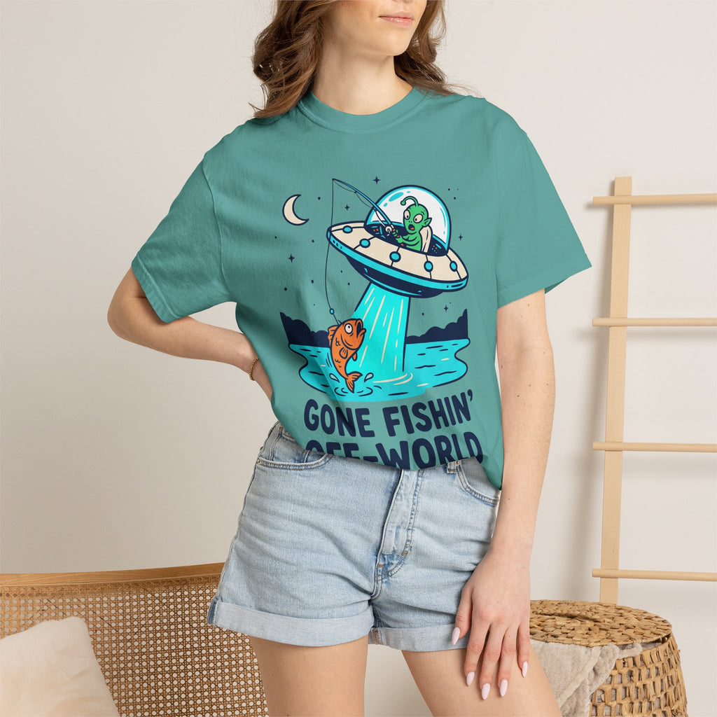 Teal graphic T-shirt on model: UFO fishing scene with alien and fish.