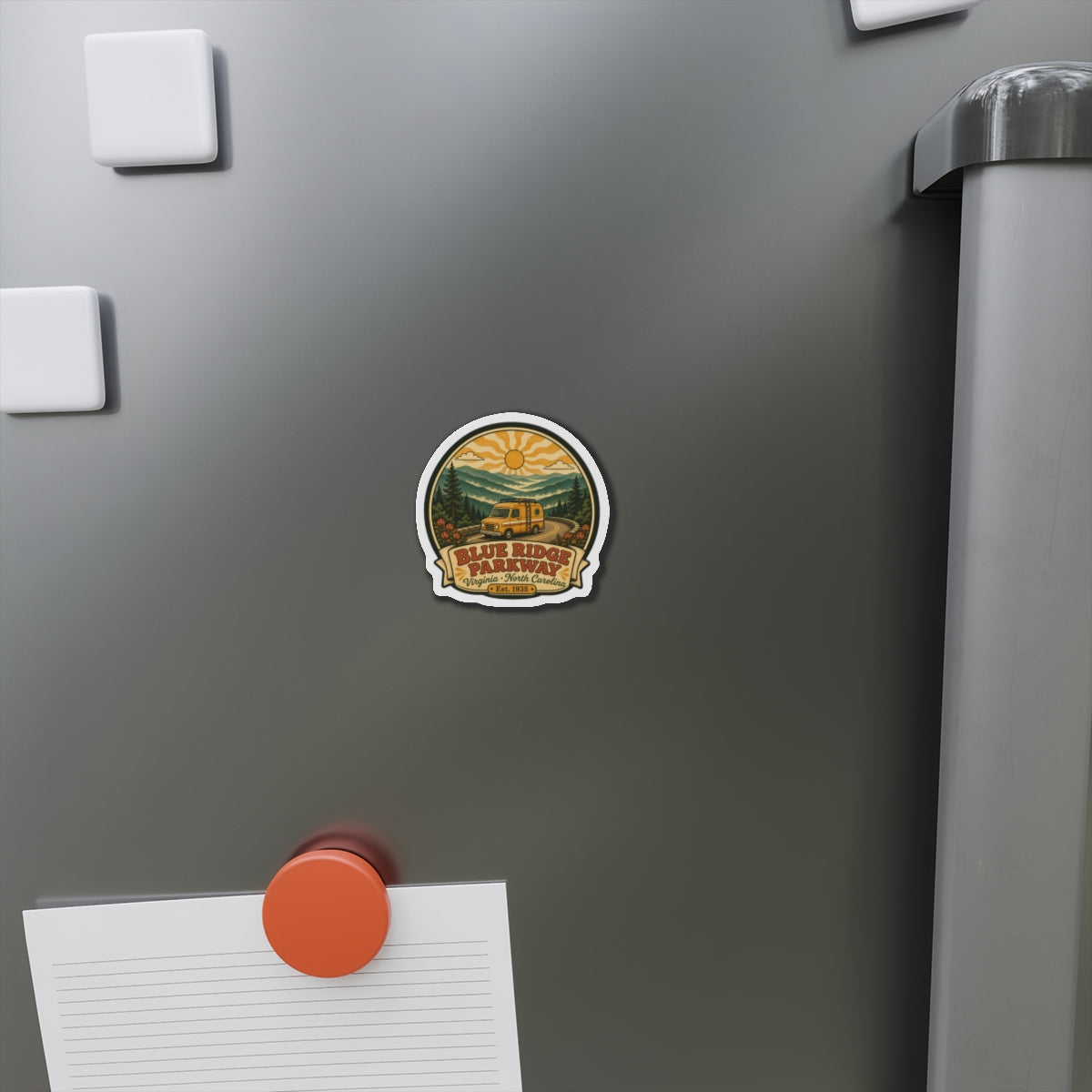 Die-cut souvenir magnet on a stainless steel fridge door with yellow camper van and mountains