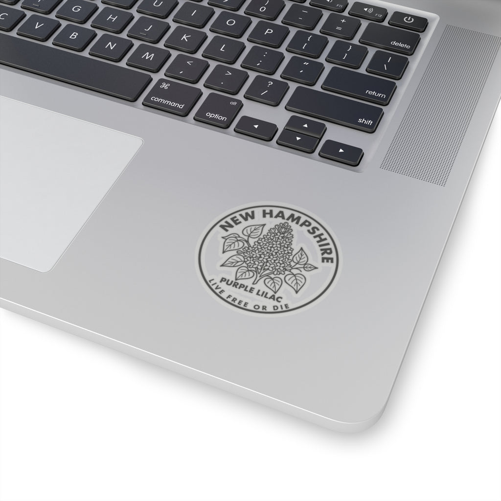 Round transparent-vinyl decal on a laptop lid, showing New Hampshire lilac logo