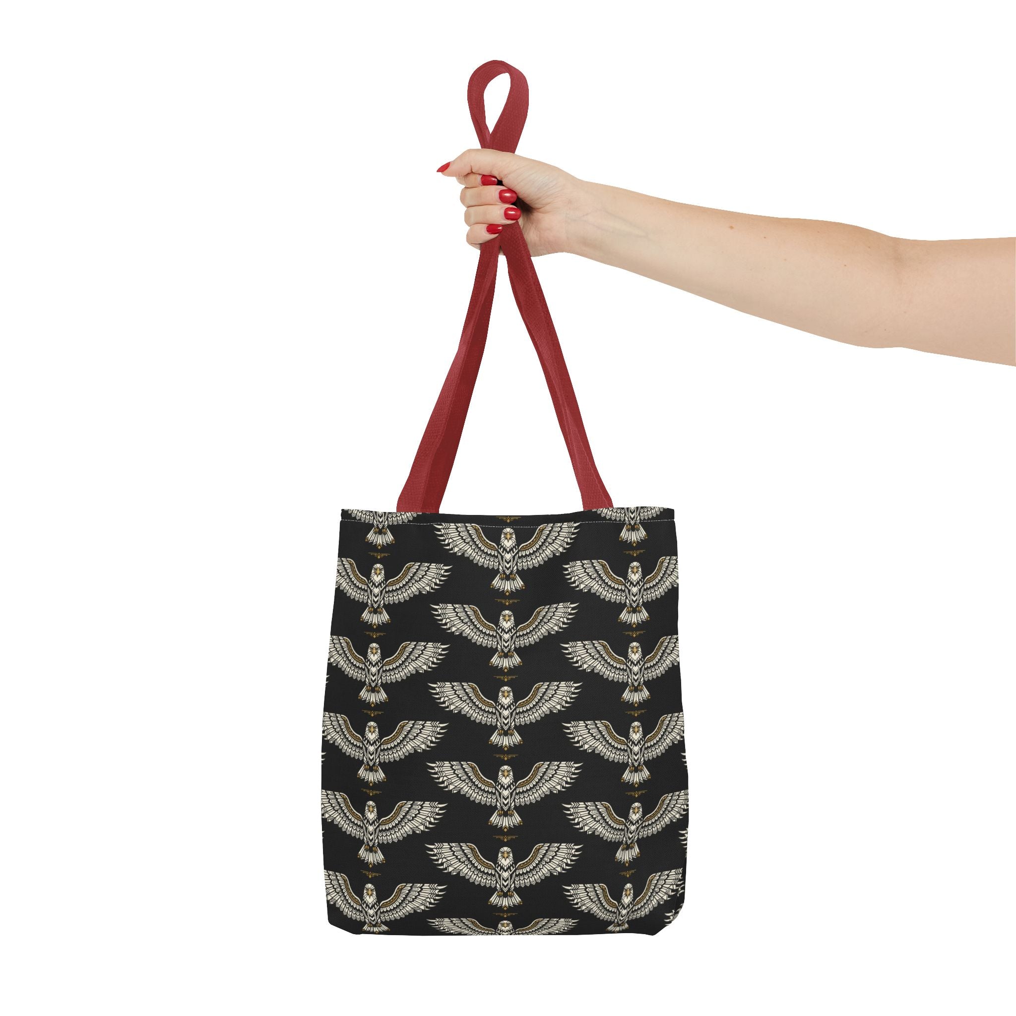 Black tote bag with gold winged scarab pattern and burgundy loop handles, hand-held