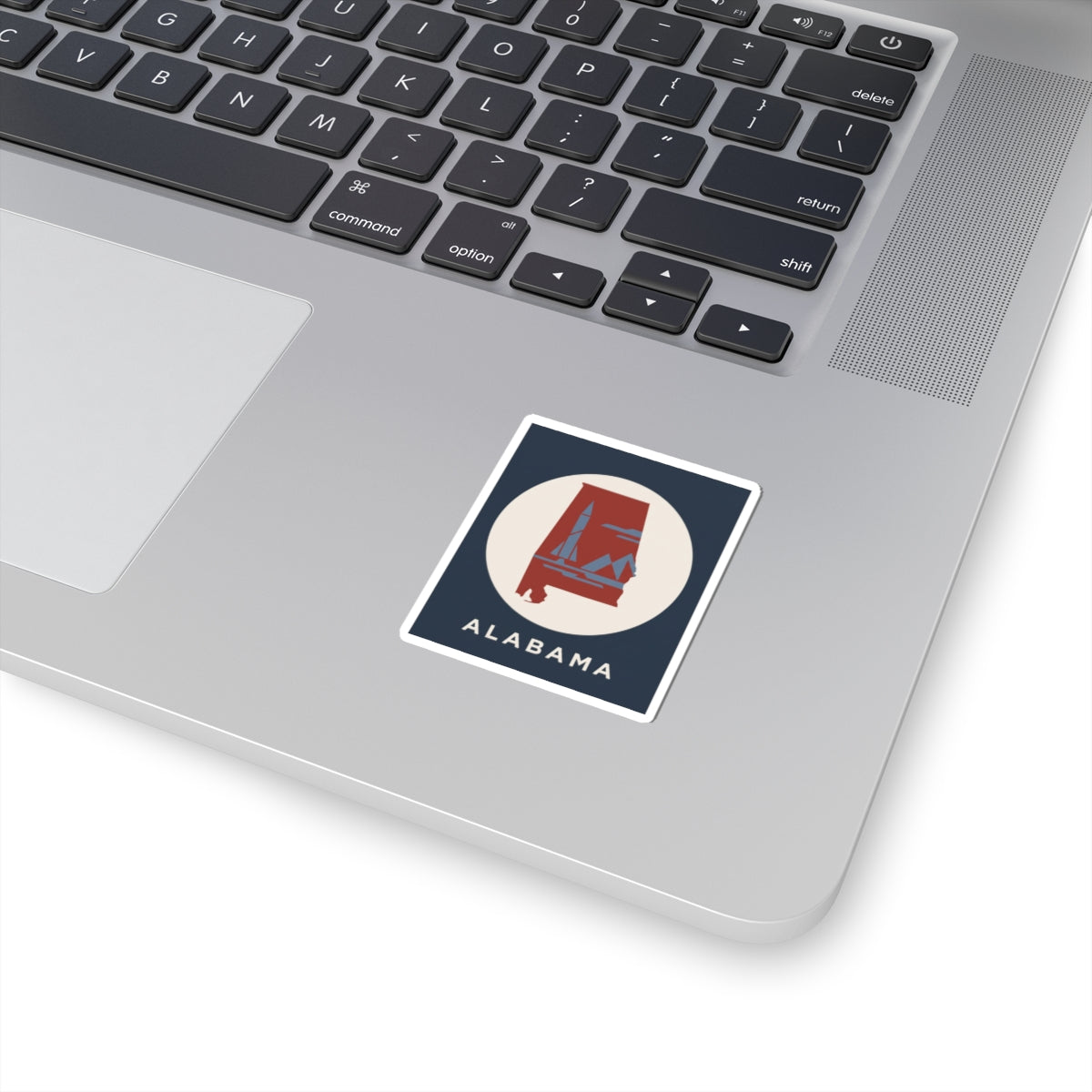 Square Alabama sticker with blue border, red rocket and landscape, white background