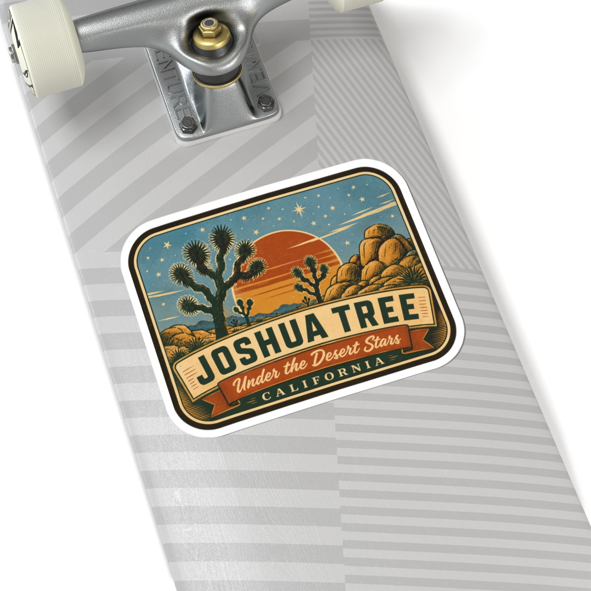 Joshua Tree sticker on a laptop trackpad area with desert rocks, sunset, and “California” text.