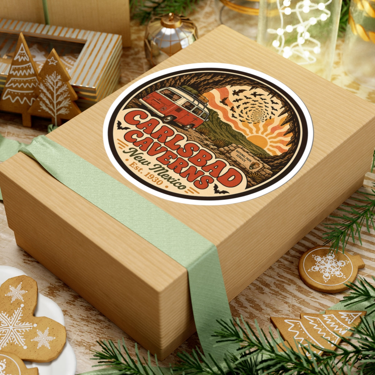 Round Carlsbad Caverns sticker on top of a wrapped gift box, orange camper van in cave scene
