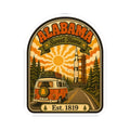Die-cut arched Alabama sticker featuring orange camper van, evergreen trees, Est. 1819.