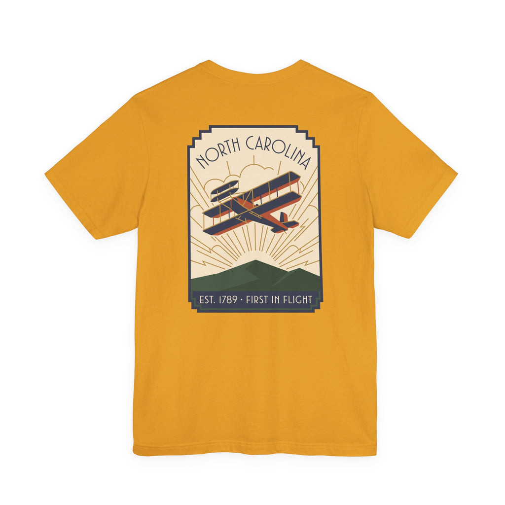 Mustard t-shirt with North Carolina biplane graphic and 'Est. 1789 - First in Flight' text