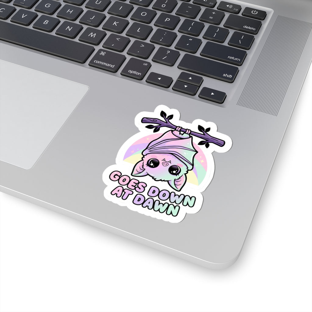 Kawaii kiss-cut vinyl sticker of a purple bat and pink hood with a pastel halo and "GOES DOWN AT DAWN"