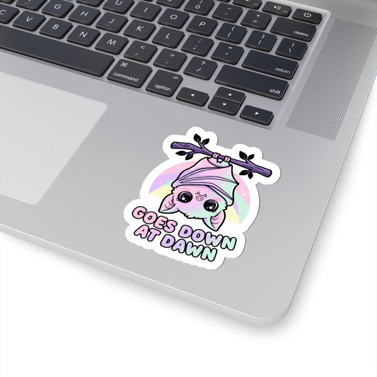 Kawaii kiss-cut vinyl sticker of a purple bat and pink hood with a pastel halo and "GOES DOWN AT DAWN"