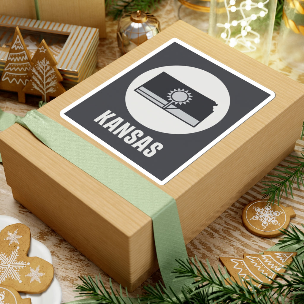 Kansas state sticker on a wrapped gift box, dark gray square with sun and wheat field