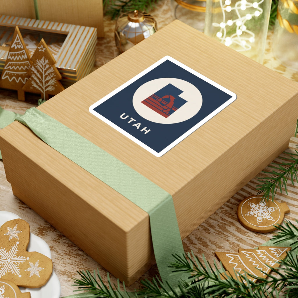 Utah arch sticker on wrapped gift: navy square with white circle, red emblem, "UTAH"