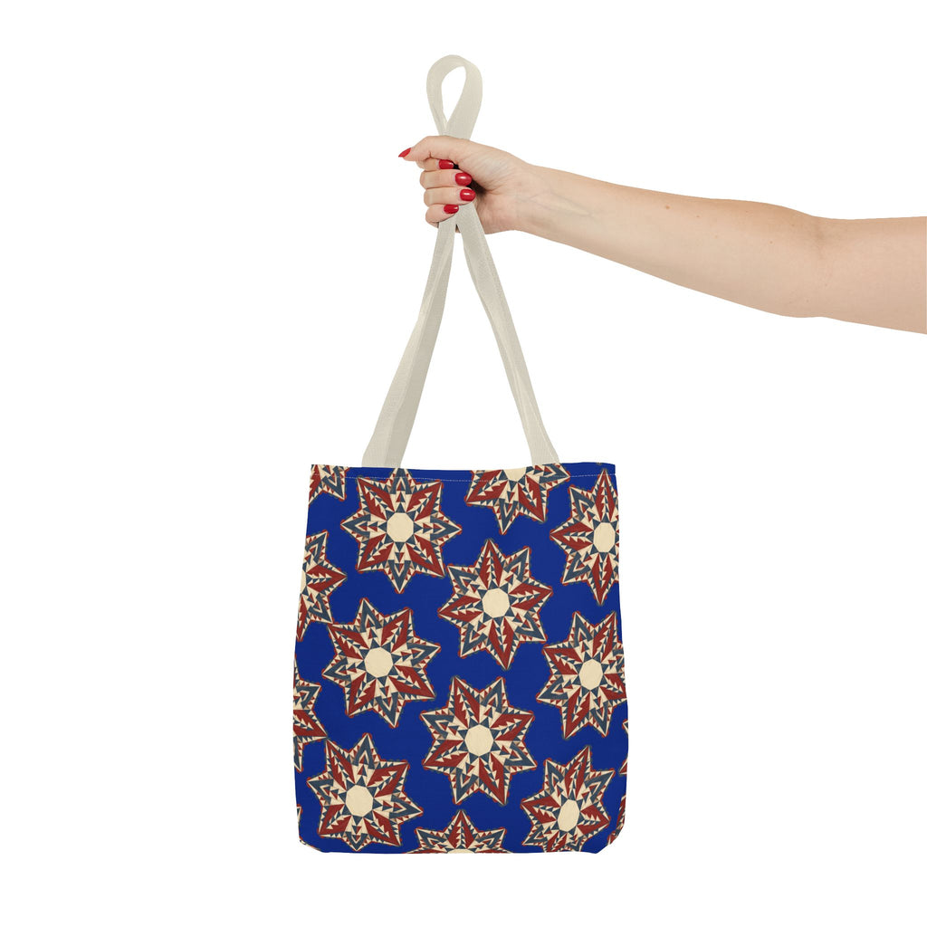 Blue starburst floral tote bag with cream and red motifs, held by two light handles