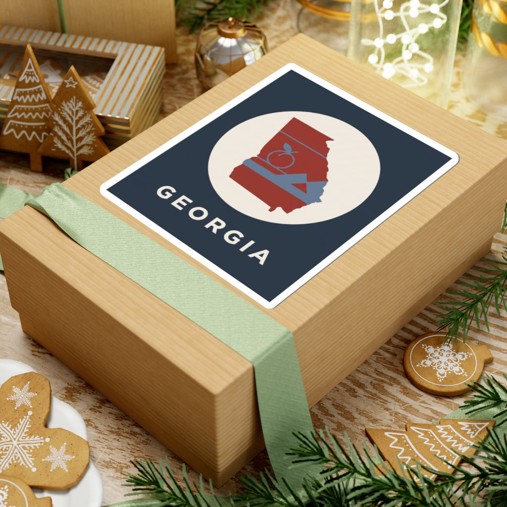 Georgia outline sticker on gift box: circular red state silhouette with peach icon, mountains, “GEORGIA”