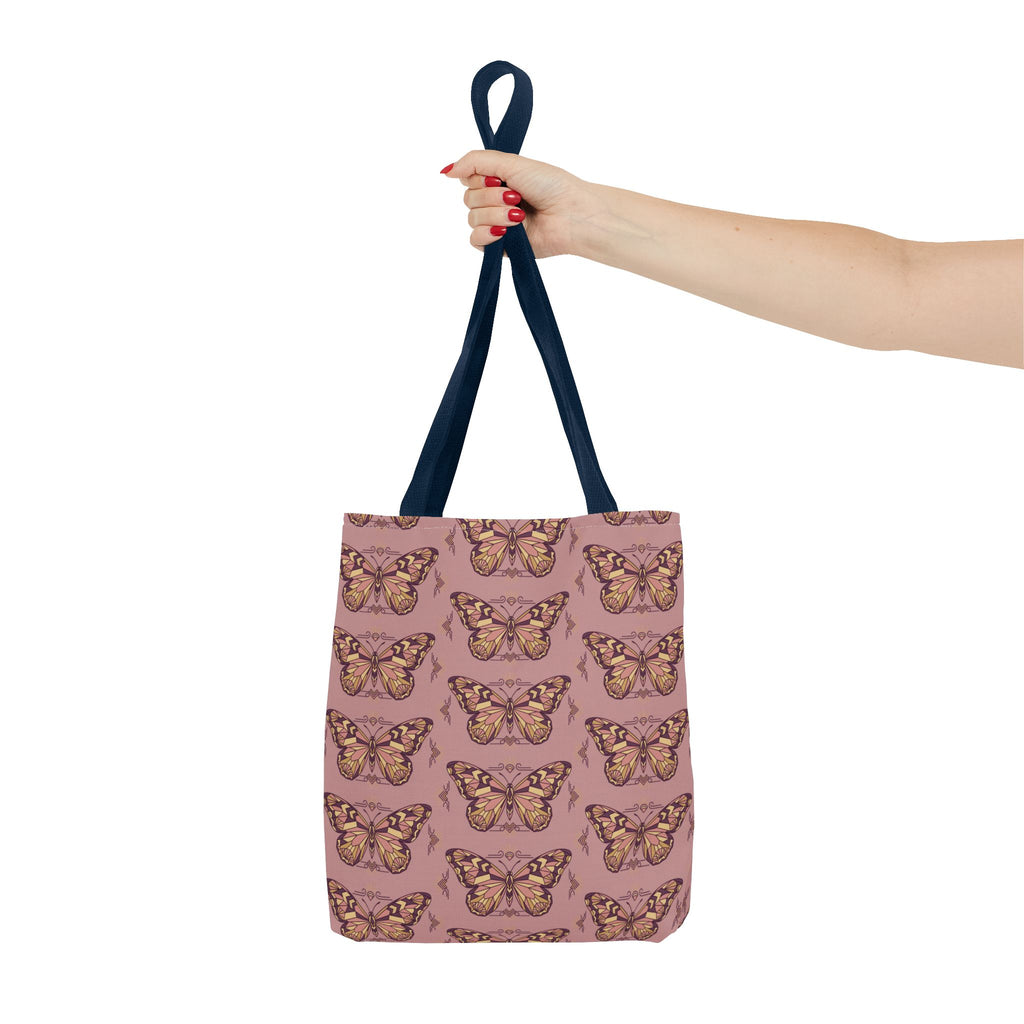 Pink tote bag with vintage butterfly print and navy handles, hand holding top
