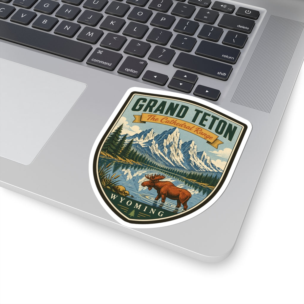 Shield-shaped travel sticker on laptop keyboard, with moose, mountains, lake, and “Wyoming” text.