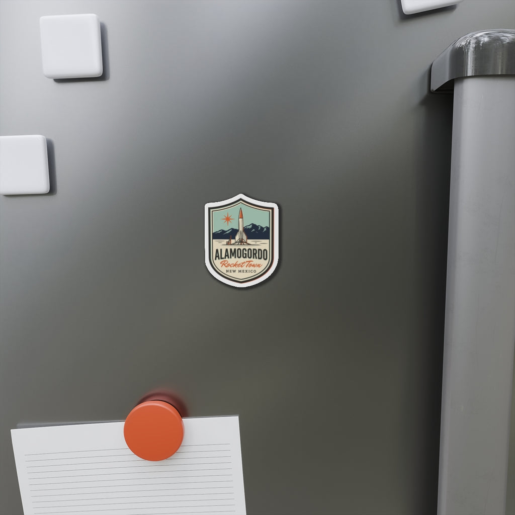 Die-cut shield magnet on stainless fridge with rocket and Alamogordo Rocket Town text