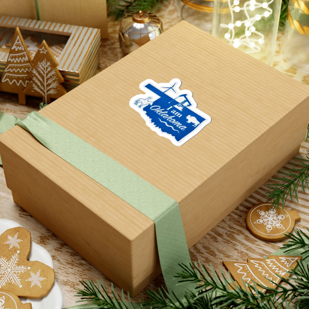 Blue “I am Oklahoma” sticker on a gift box, with airplane and oil rig graphic