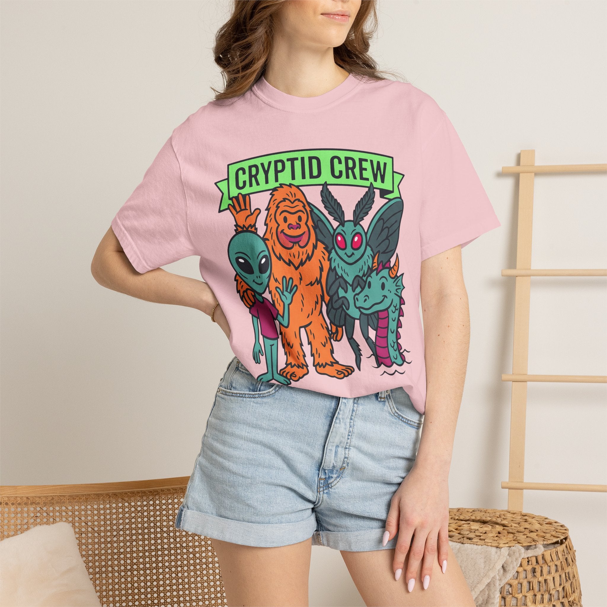 Light pink crew neck t-shirt with multicolor cryptid graphic and green 'CRYPTID CREW' text