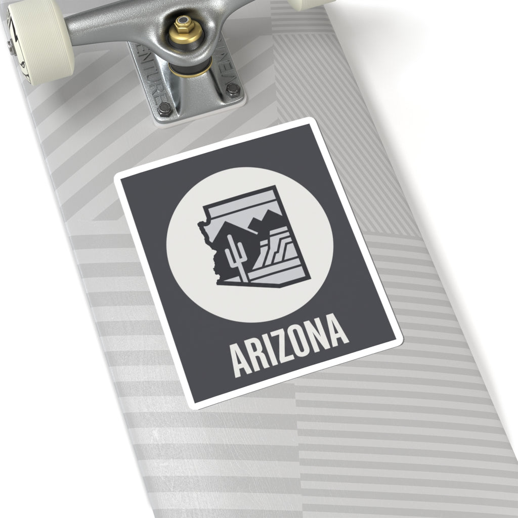 Arizona badge sticker angled: dark square with white circle desert cacti logo and ARIZONA text