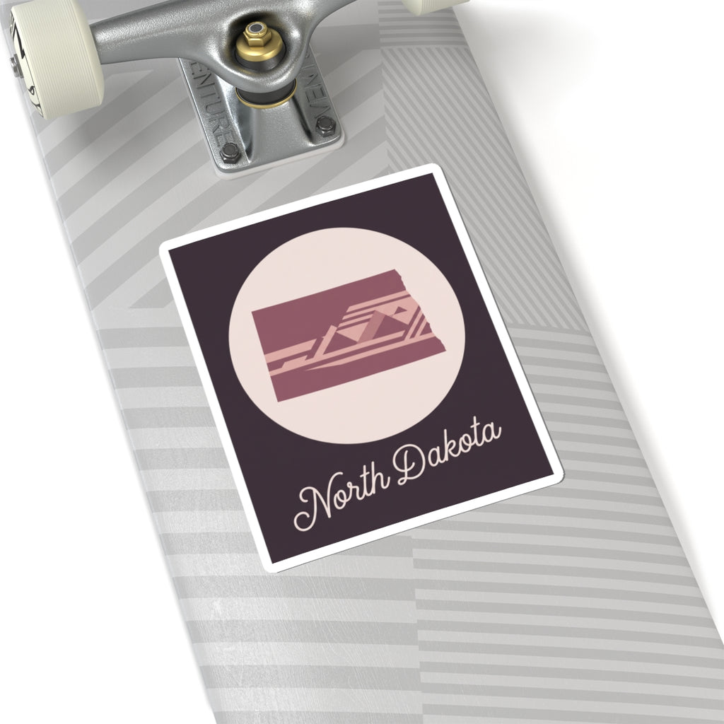 North Dakota square decal on striped surface: pale circle with maroon state scene