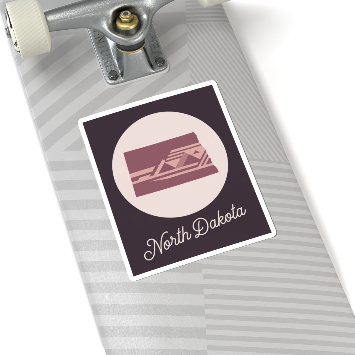 North Dakota square decal on striped surface: pale circle with maroon state scene