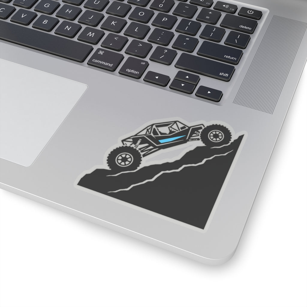Die-cut sticker on laptop trackpad area: off-road truck and blue stripe on dark road