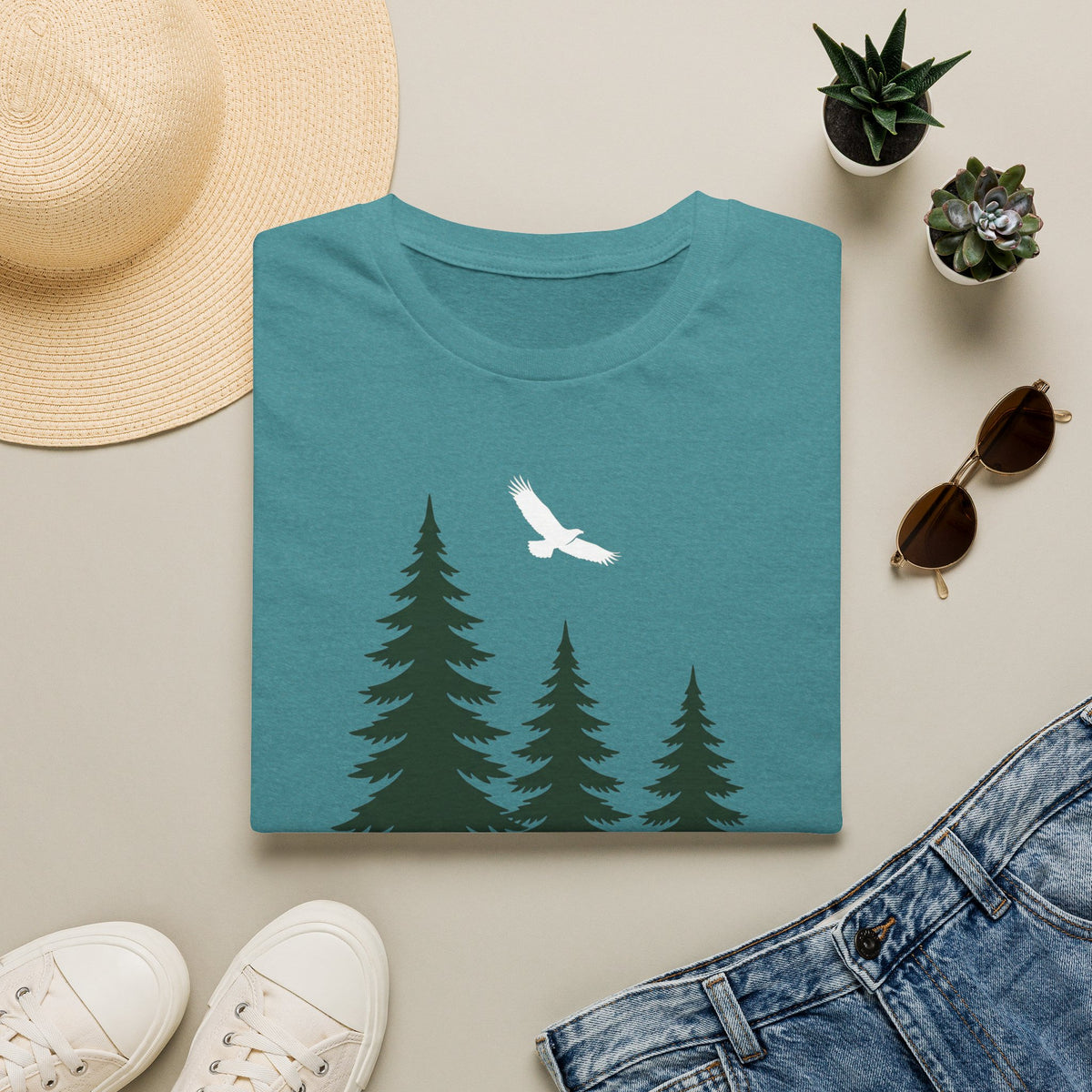 Teal t-shirt with pine tree scene and a white soaring bird graphic