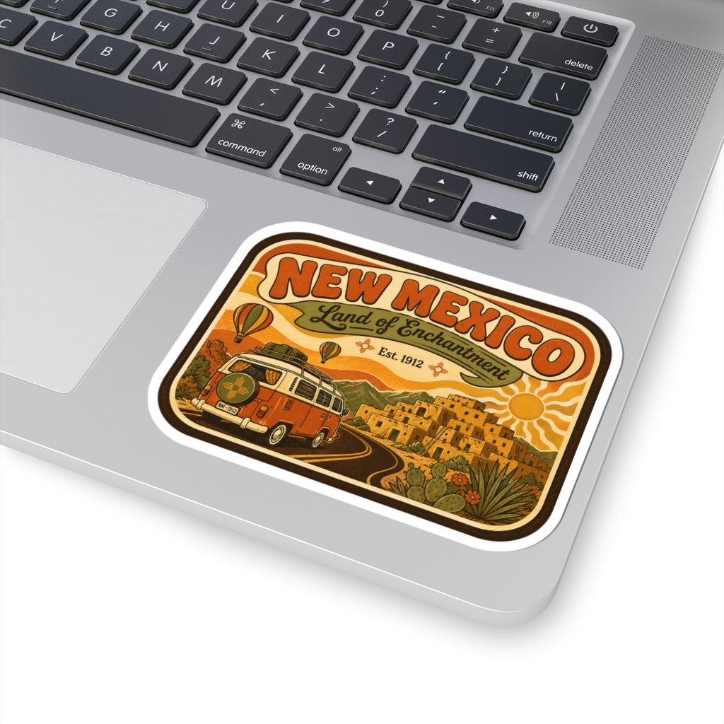 Die-cut New Mexico sticker featuring orange camper, desert village, and “Land of Enchantment”