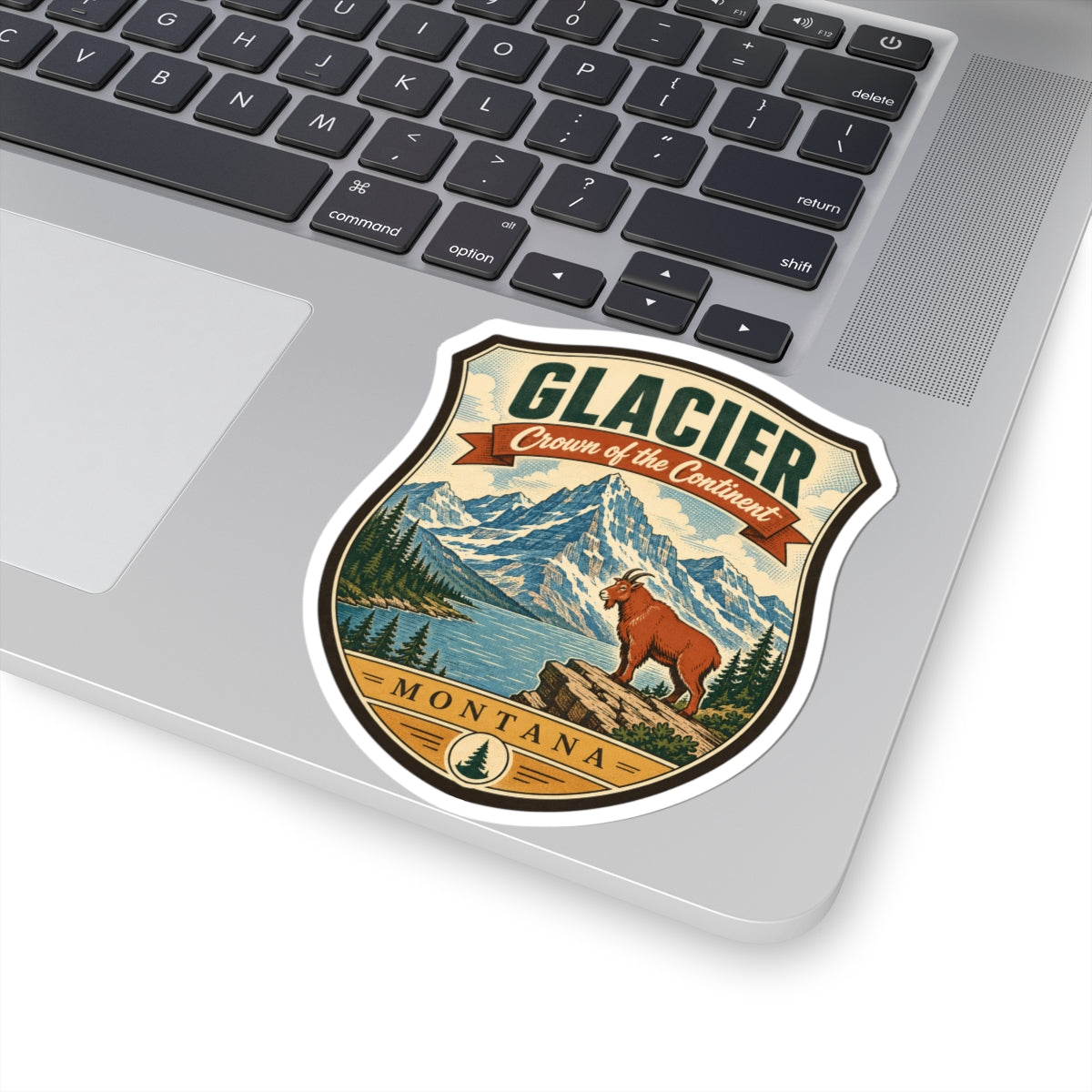Shield-shaped sticker with “GLACIER” and “Crown of the Continent,” mountains, pine trees, brown dog