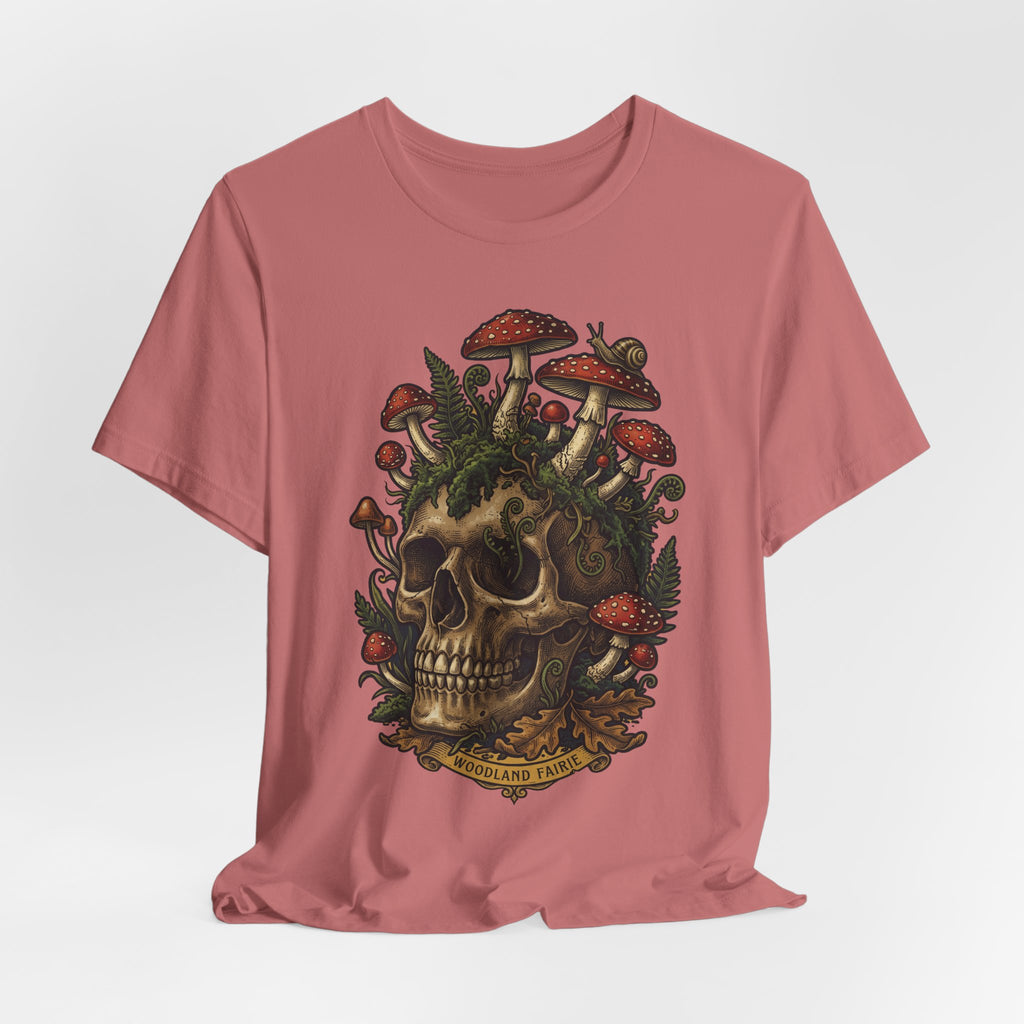 Mushroom skull T-shirt rosa: calavera con setas rojas y vegetación tipo bosque.