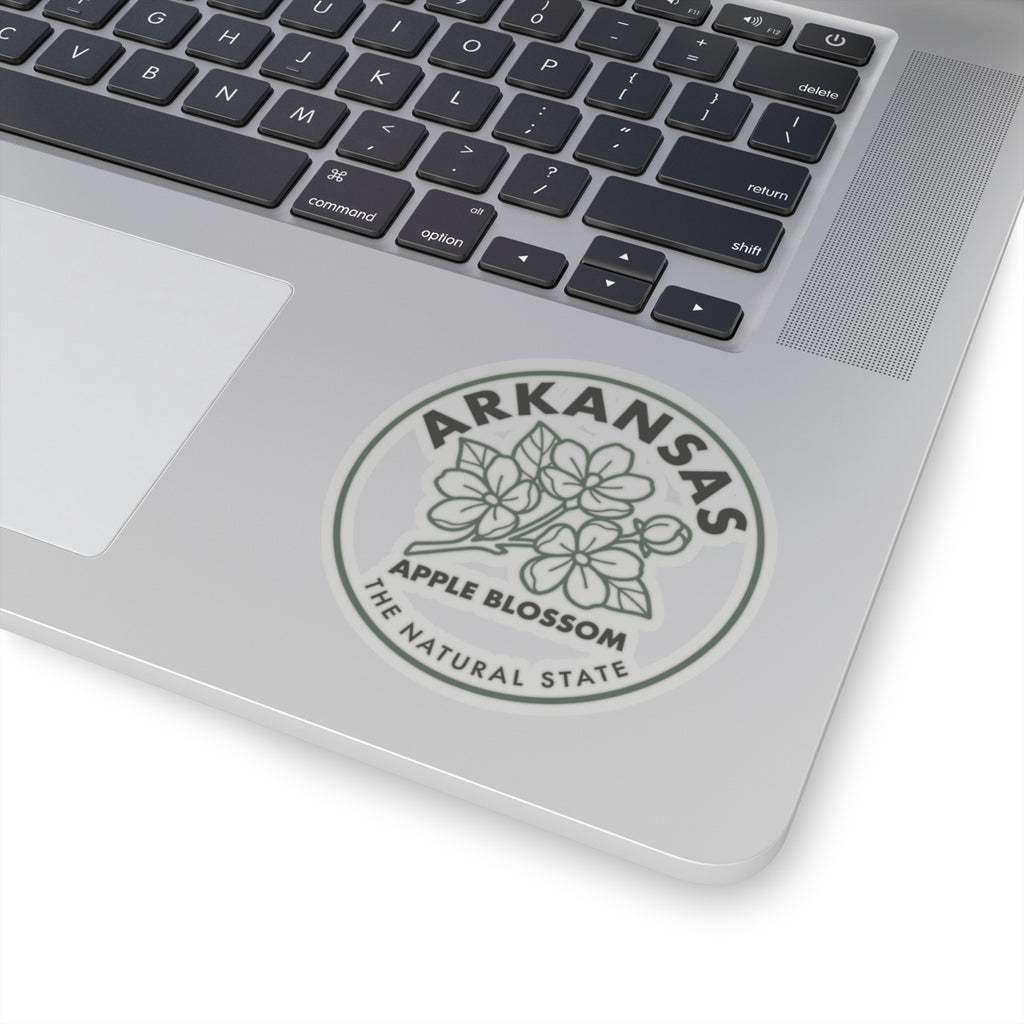 Round Arkansas apple blossom decal on laptop surface with floral artwork and “ARKANSAS” text.