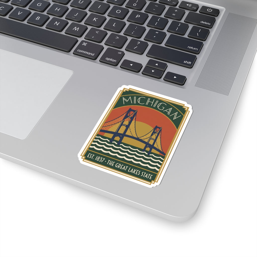 Michigan bridge die-cut sticker on a laptop keyboard, green banner and blue wave design