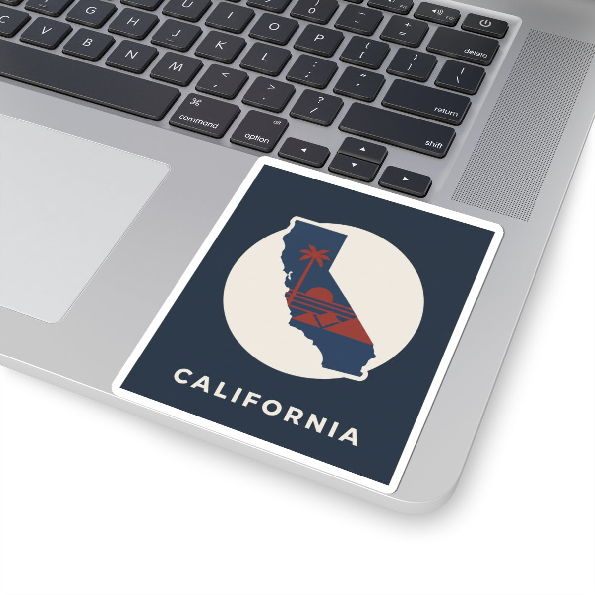 California silhouette sticker on laptop keyboard: navy square with white circle and "CALIFORNIA"