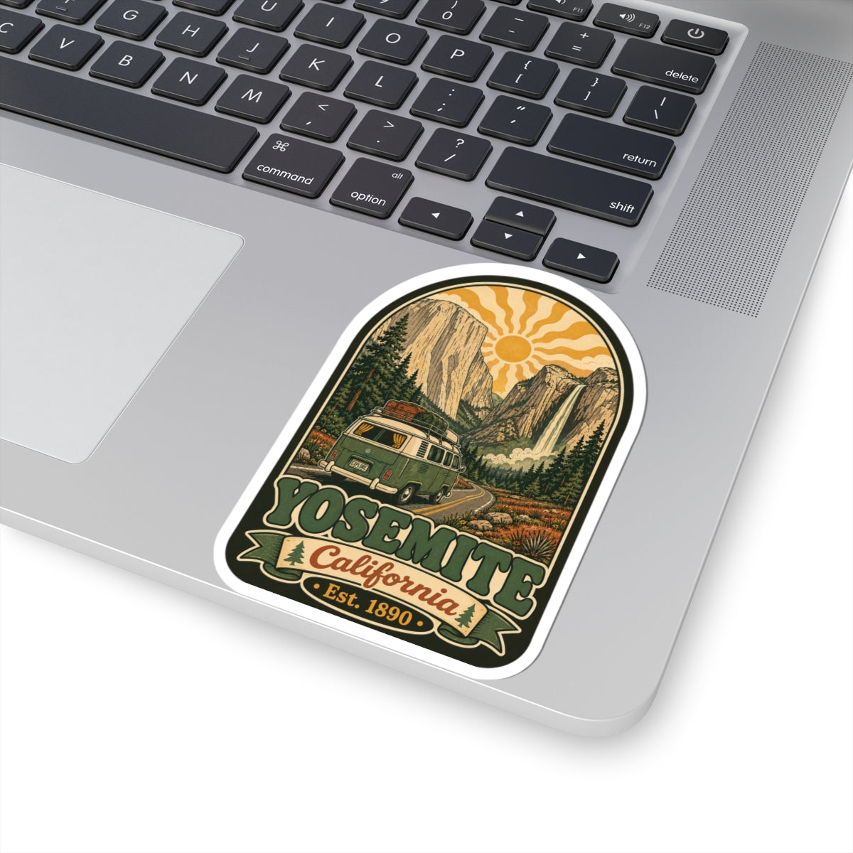 Arched landscape sticker on a laptop keyboard, featuring camper van and “Est. 1890”