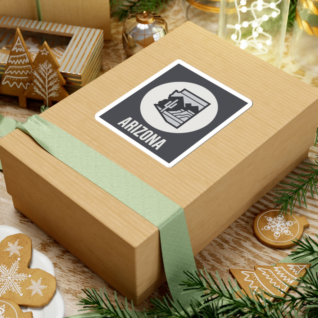Arizona badge sticker on gift wrap: dark square with white circle desert graphic and ARIZONA