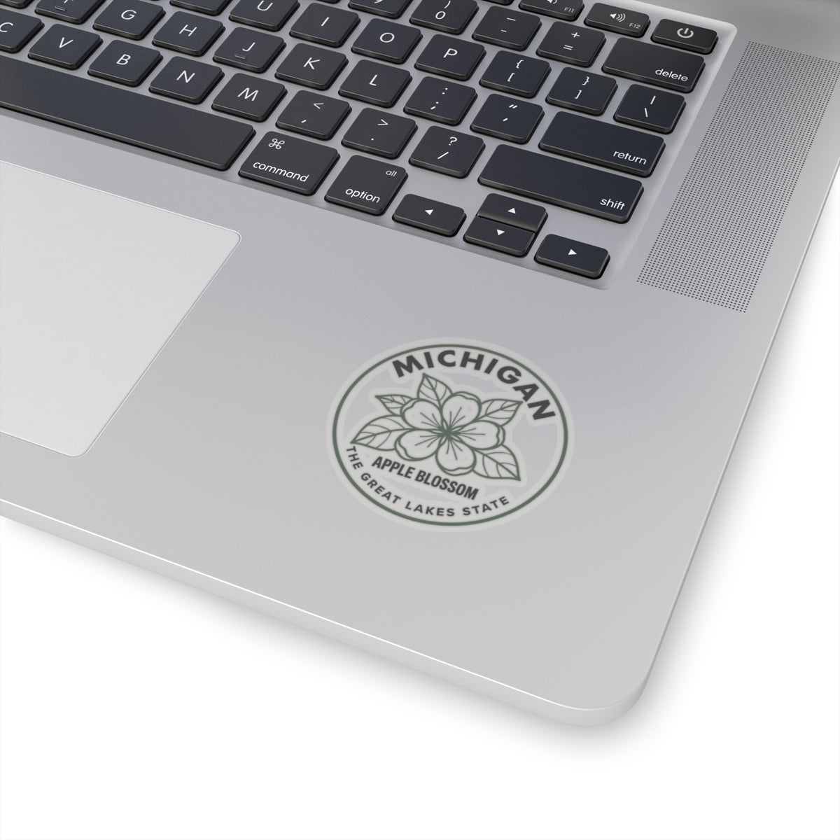 Transparent vinyl Michigan apple blossom sticker on laptop lid, round gray seal design