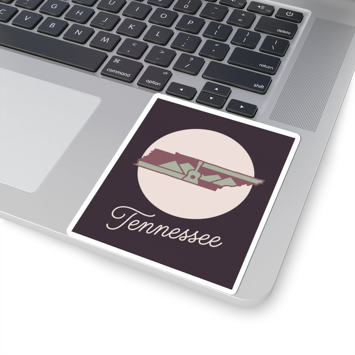Tennessee sticker on laptop surface featuring state silhouette and “Tennessee”