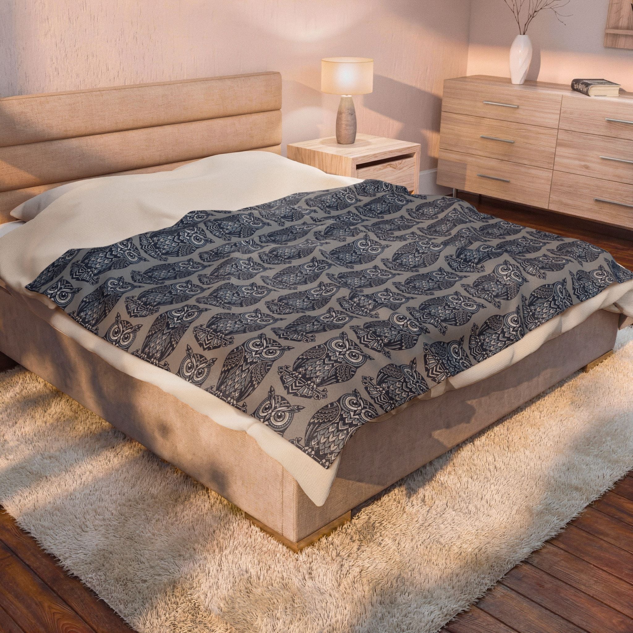 Blue owl-pattern plush blanket with repeating owl prints on bed, folded at edges
