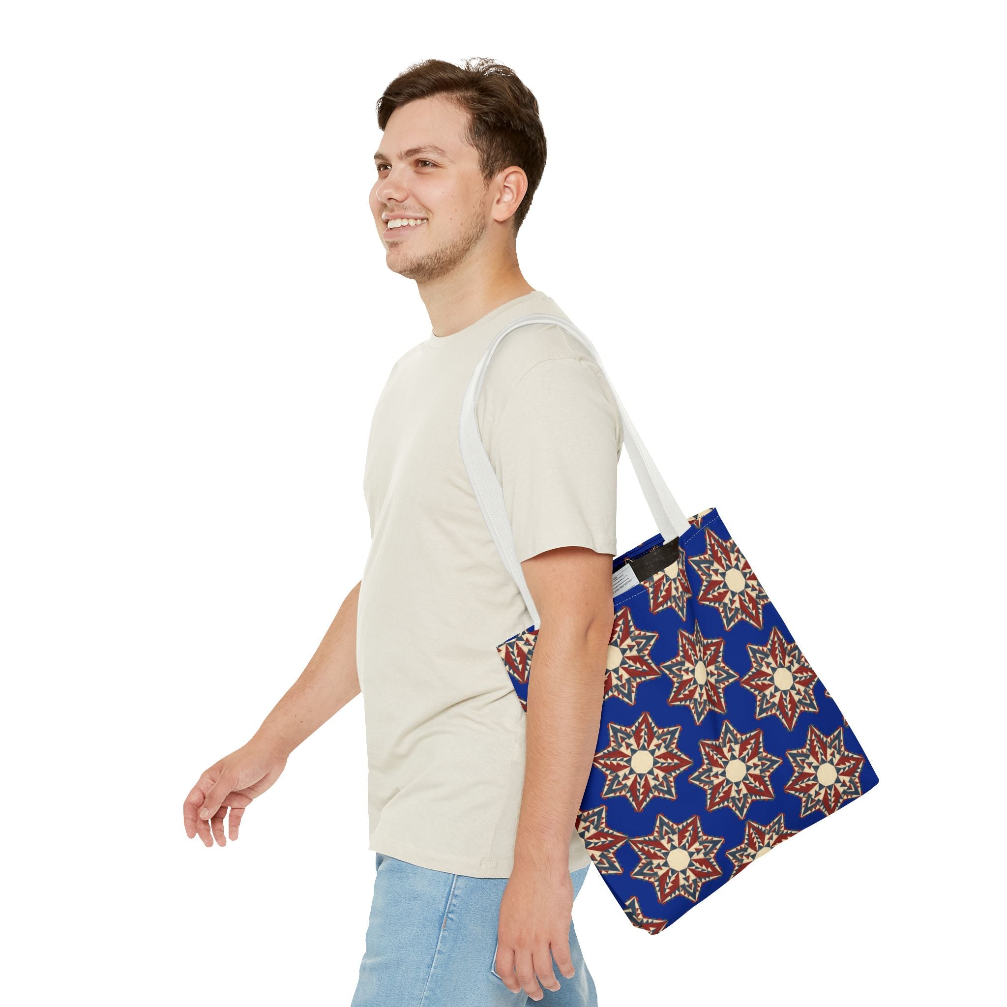 Blue starburst floral tote bag with blue strap worn by a person over a T-shirt
