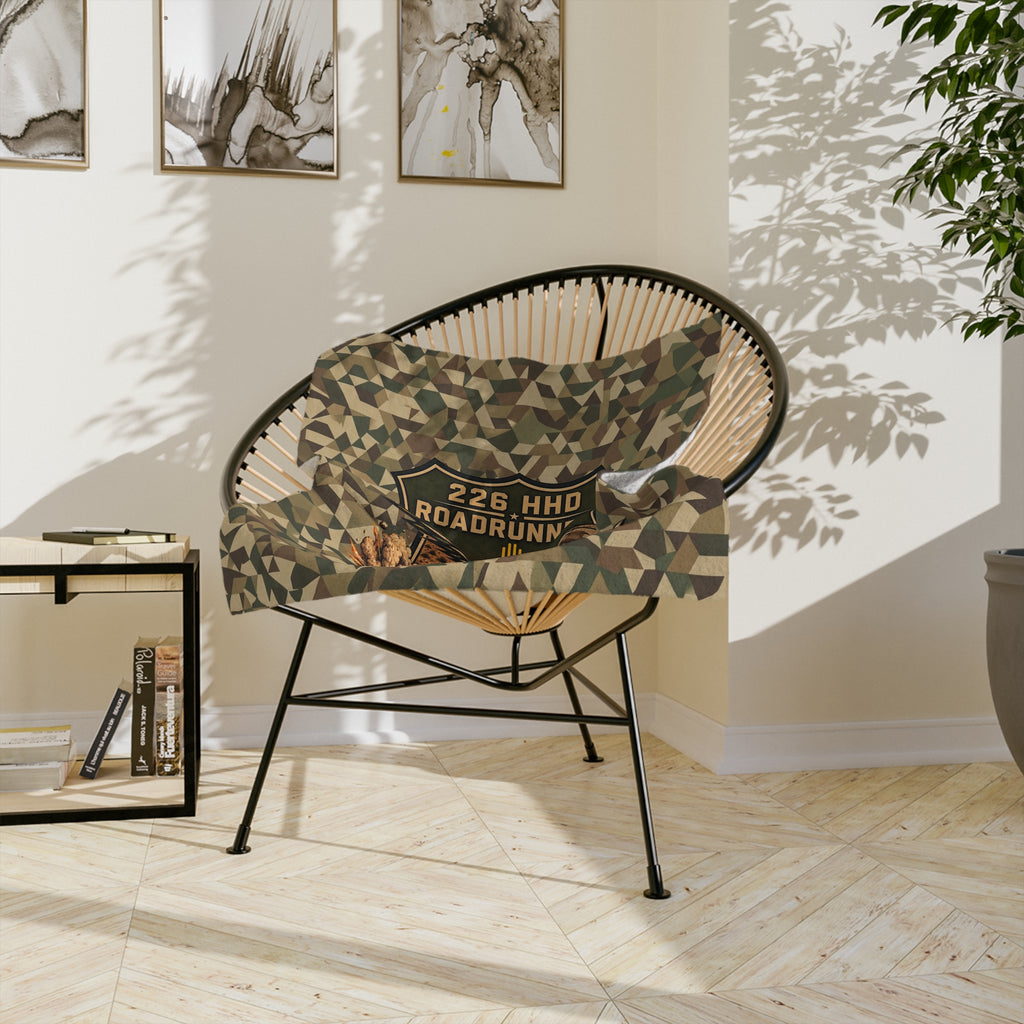 Camo microfiber blanket draped over chair with central patch graphic and golden emblem